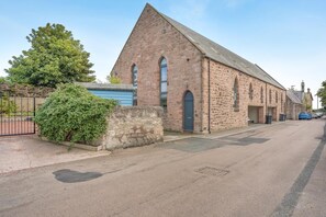 A stone building with a triangular roof, a gated entrance, and a paved street. - 3 Bed in Spittal (oc-b45905) (Spittal)