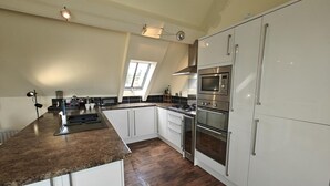 A modern kitchen with white cabinetry, a granite countertop, stainless steel appliances, and a skylight. - 3 Bed in Spittal (oc-b45905) (Spittal)