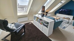 A modern loft apartment with skylights, a sofa, a TV, and a bookshelf. - 3 Bed in Spittal (oc-b45905) (Spittal)