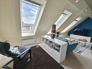 A modern loft apartment with skylights, a sofa, a TV, and a bookshelf. - 3 Bed in Spittal (oc-b45905) (Spittal)