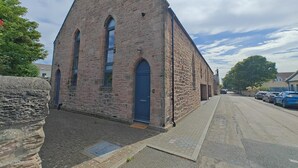A stone building with a steep gabled roof, a blue door, and a paved street in front. - 3 Bed in Spittal (oc-b45905) (Spittal)