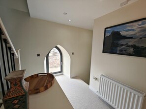A hallway with a wooden floor, a radiator, and a framed picture on the wall. - 3 Bed in Spittal (oc-b45905) (Spittal)