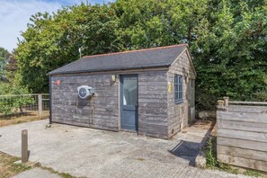 A small wooden building with a door, a window, and an air conditioning unit attached to the wall. - 1 Bed in St Austell (oc-h45926) (High Street)