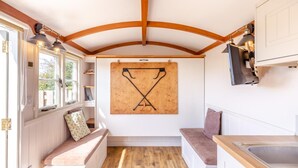 Una cocina compacta con vigas de madera, suelo de madera, un tablón de anuncios con ganchos y un banco con cojines.