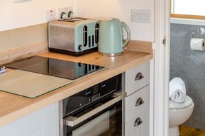 A compact kitchenette with a toaster, kettle, and a built-in oven. - 1 Bed in St Austell (oc-s45927) (High Street)