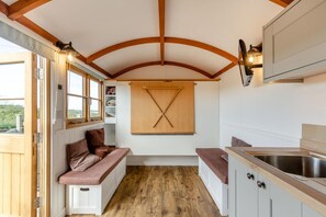 A compact kitchen with wooden beams, a bench, and a window. - 1 Bed in St Austell (oc-s45927) (High Street)