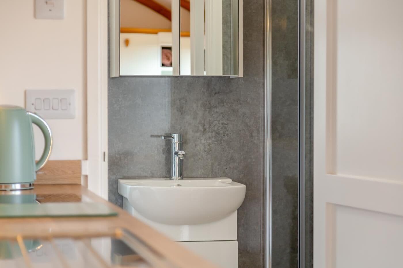 A bathroom with a white sink, a chrome faucet, and a mirror above it.