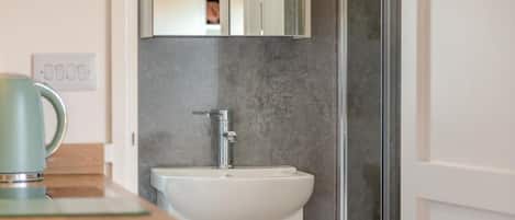 A bathroom with a white sink, a chrome faucet, and a mirror above it.