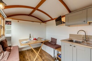 A compact kitchen with a wooden table, a bench, and a built-in TV. - 1 Bed in St Austell (oc-s45927) (High Street)
