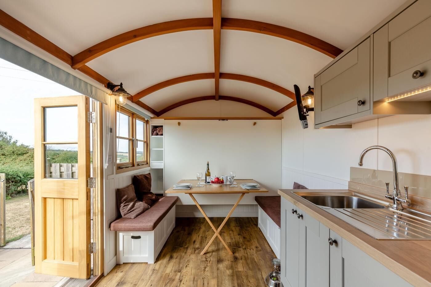 Une cuisine compacte dotée d’un banc intégré, de poutres en bois au plafond et d’un évier avec un robinet moderne.
