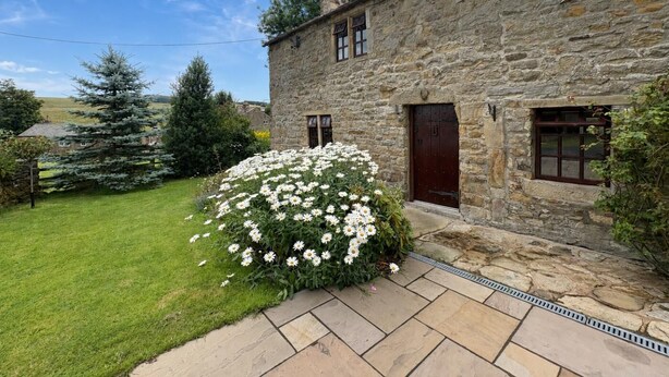 A stone building with a well-maintained lawn and a large bush of white flowers. - 2 Bed in Bolton By Bowland (oc-m45938) (Grindleton)