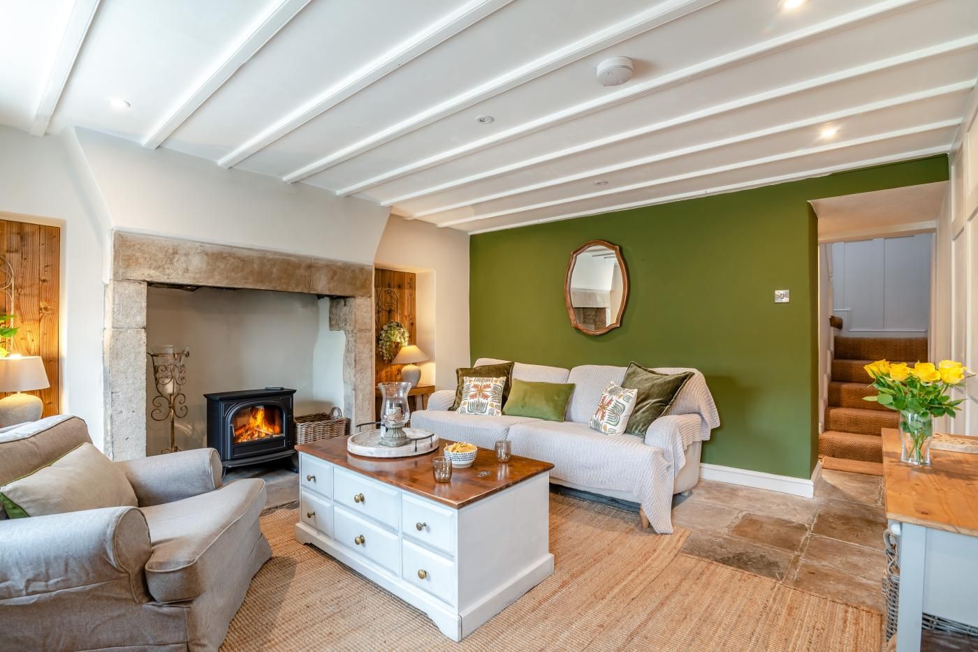 A living room with a fireplace, a sofa, a coffee table, and a staircase leading to another room.