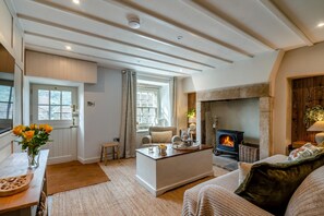 Una sala de estar acogedora con chimenea, comedor y cocina con vigas de madera en el techo.