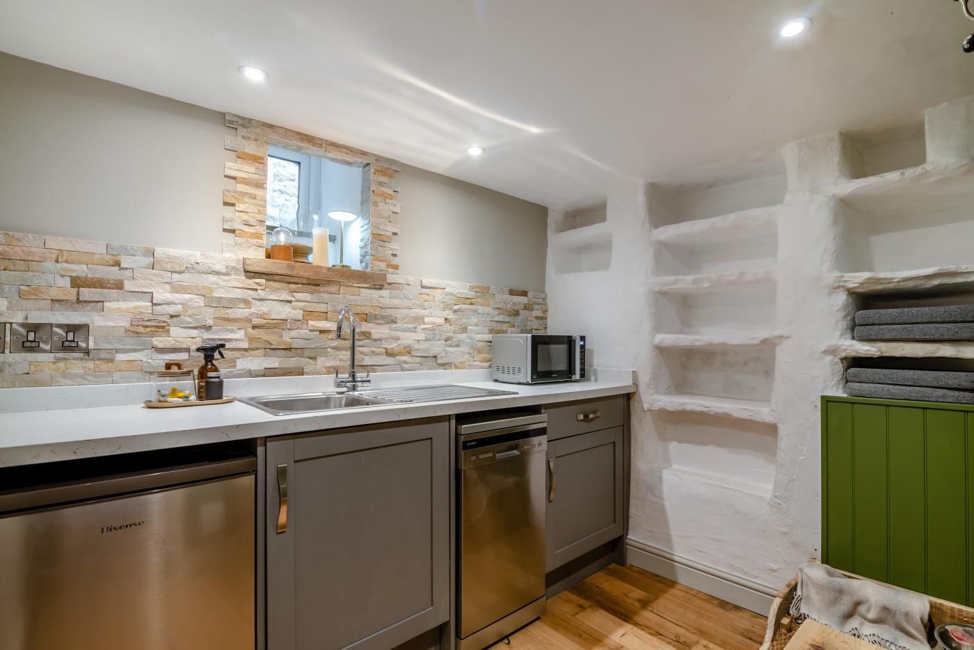 A kitchen with a stone backsplash, stainless steel appliances, and a microwave on the counter.