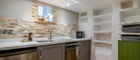A kitchen with a stone backsplash, stainless steel appliances, and a microwave on the counter.