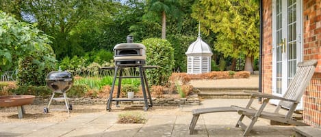 En uteplats med en grill, en pergola och en byggnad av tegel.