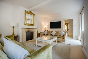 Ein Wohnzimmer mit Kamin, einer Couch, einem Couchtisch und einem Fernseher.