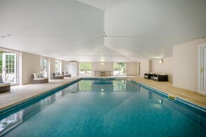 Ein großer, überdachter Pool mit freier Sicht auf die Umgebung, inklusive Sitzgelegenheiten und einer Tür.