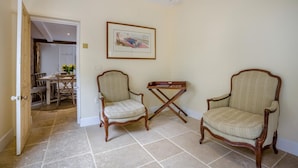 Une pièce comprenant deux fauteuils rembourrés, une petite table et un tableau encadré accroché au mur.