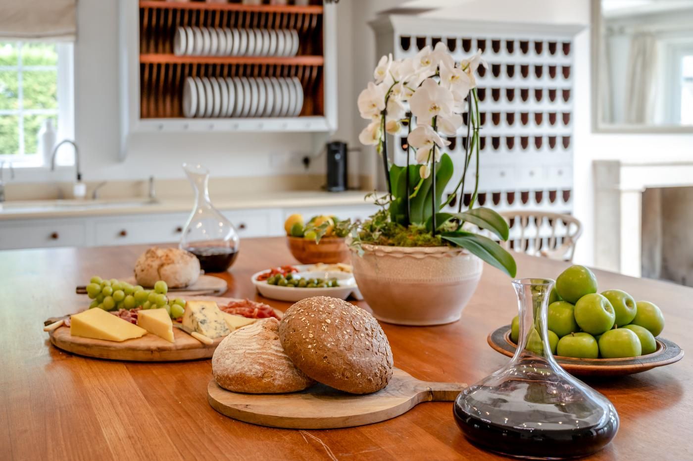 A kitchen counter with various food items, a potted plant, and a wine bottle.