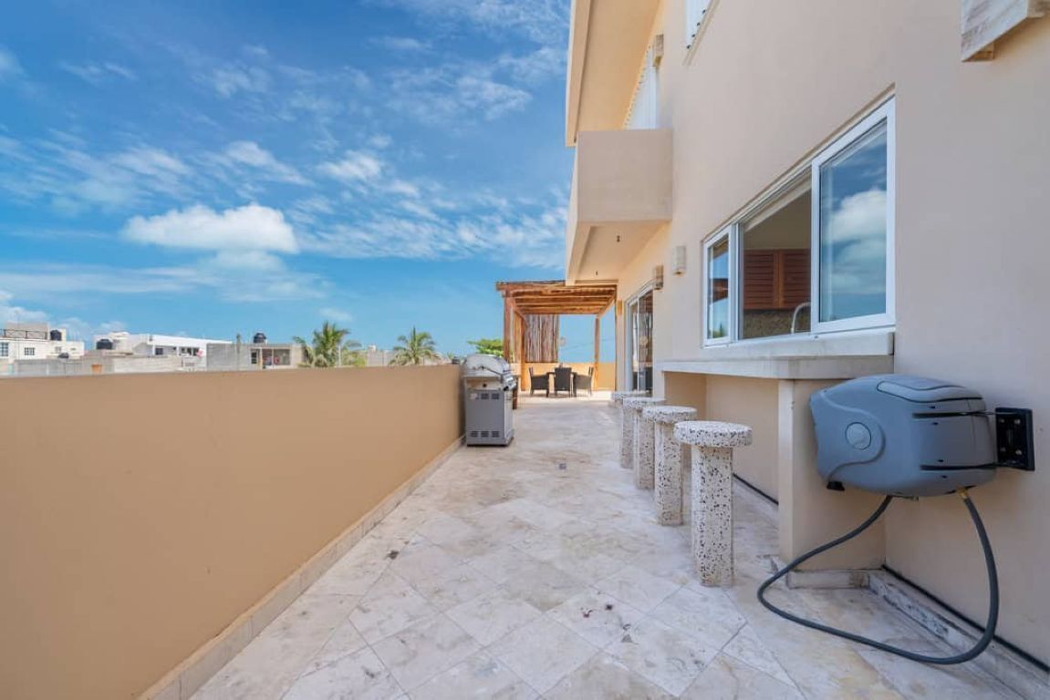 A rooftop terrace with a barbecue area, outdoor seating, and a water dispenser.