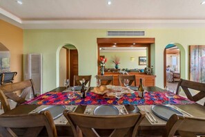 A dining area with a table set for four, chairs, and a kitchen in the background.