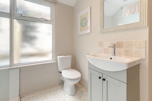 A bathroom with a toilet, sink, and frosted window. - 4 Bed in St. Ives (oc-s46007) (Saint Ive)