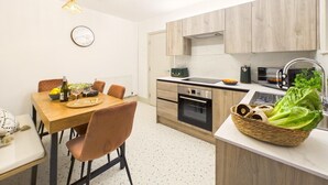 Moderni keittiö, jossa on puiset kaapit, sisäänrakennettu uuni ja pesuallas.