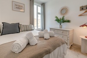 A neatly made bed with rolled towels, a bedside plant, and a framed sign on the wall. - 4 Bed in St. Ives (oc-s46007) (Saint Ive)