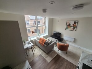 Ein modernes Wohnzimmer mit einer Couch, einem Couchtisch, einem Fernseher und einem Kamin.