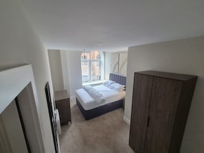 Ein Schlafzimmer mit Bett, Kleiderschrank, Fenster und Tür.