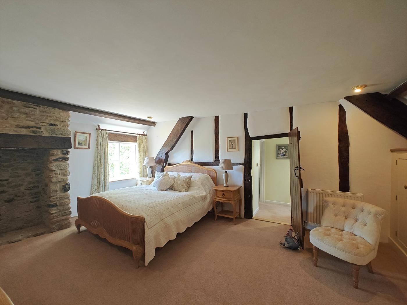A bedroom with a stone wall, a bed, a chair, and a door.