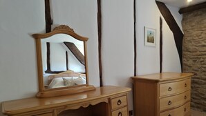 A wooden dresser with drawers and a mirror, a bench with a cushioned seat, and a stone wall. - 2 Bed in Buckerell (oc-h45977) (Buckerell)