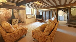 A rustic living room with exposed wooden beams, a stone wall, a fireplace, and a television. - 2 Bed in Buckerell (oc-h45977) (Buckerell)