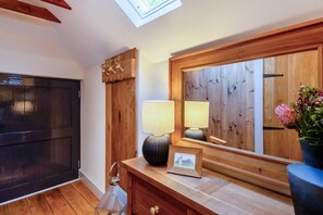 A room with a wooden door, a mirror, a lamp, and a vase with flowers. - 1 Bed in Botus Fleming (oc-f45947) (Botusfleming)