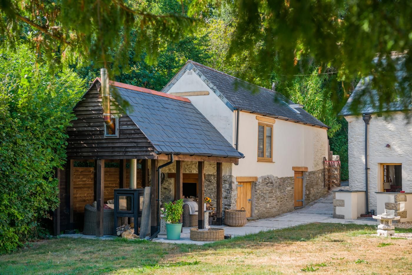 A rustic house with a sloped roof, a wooden porch, and a stone wall.
