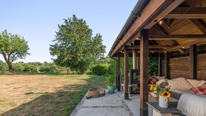 An outdoor patio area with a covered seating area, a fire pit, and a view of a grassy field and trees. - 1 Bed in Botus Fleming (oc-f45947) (Botusfleming)
