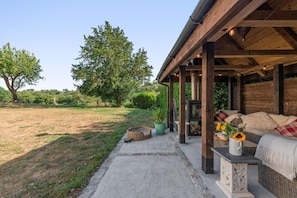 An outdoor patio area with a covered seating area, a fire pit, and a view of a grassy field and trees. - 1 Bed in Botus Fleming (oc-f45947) (Botusfleming)