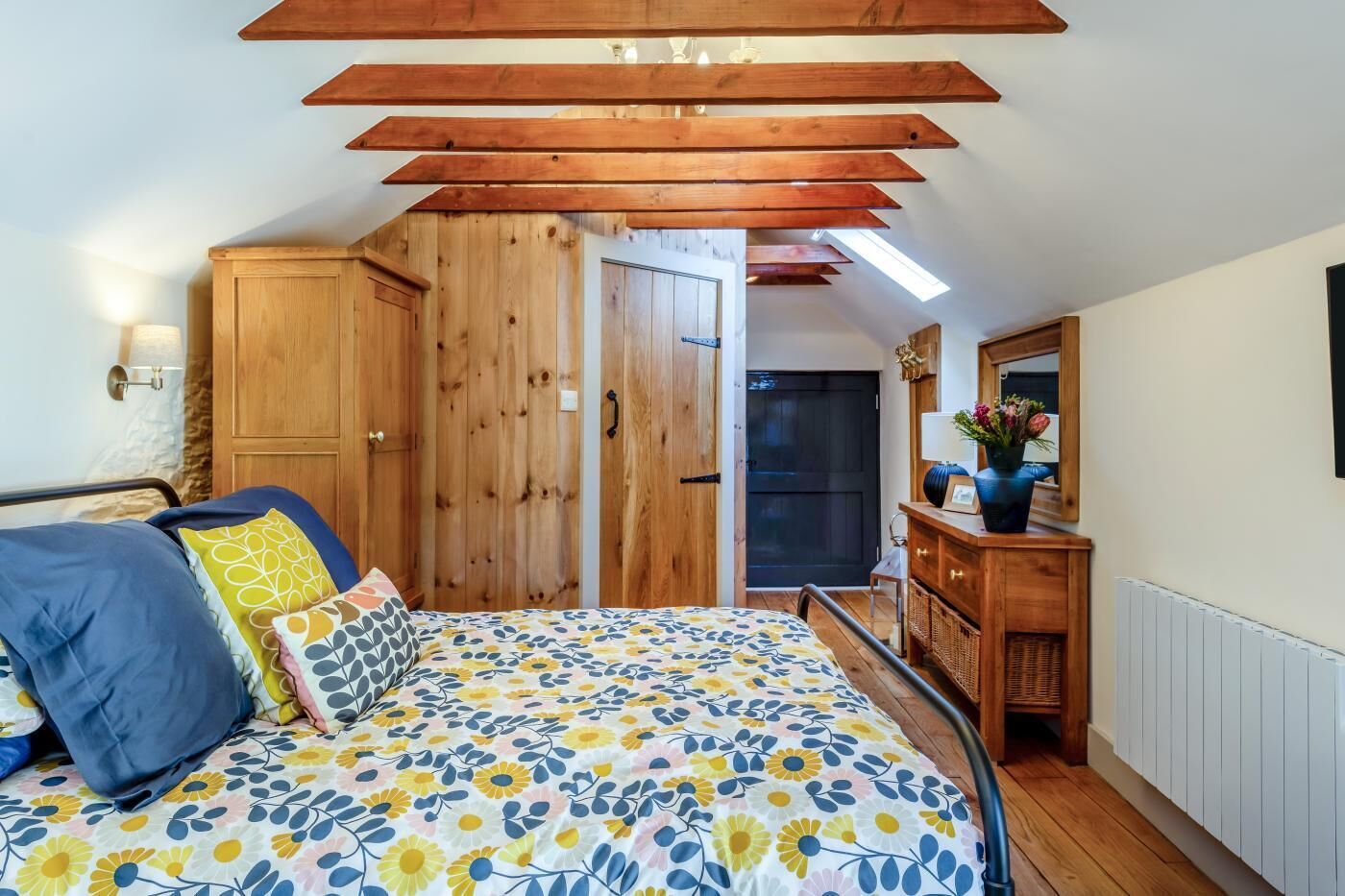 Um quarto com cama, guarda-roupa de madeira e penteadeira com espelho.