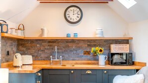 A kitchen with a wooden countertop, a sink, a clock, and a sign that reads 'CHATEAU BEL AIR.' - 1 Bed in Botus Fleming (oc-f45947) (Botusfleming)