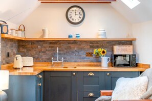 A kitchen with a wooden countertop, a sink, a clock, and a sign that reads 'CHATEAU BEL AIR.' - 1 Bed in Botus Fleming (oc-f45947) (Botusfleming)