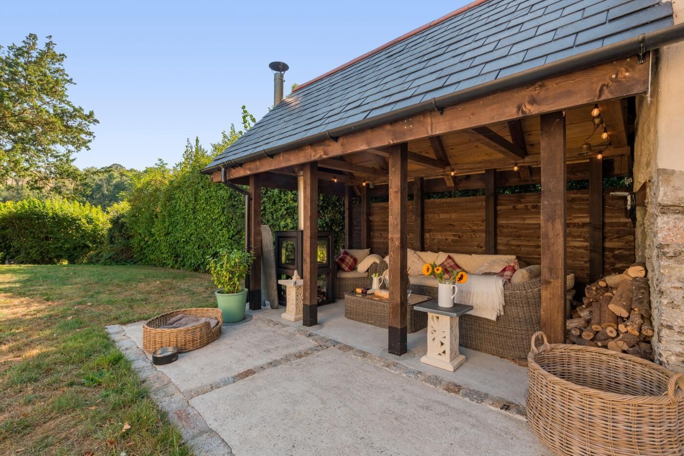 A rustic wooden building with a covered patio area, outdoor seating, and a garden.