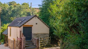 A small stone building with a dark door and steps leading up to it, surrounded by greenery. - 1 Bed in Botus Fleming (oc-f45947) (Botusfleming)