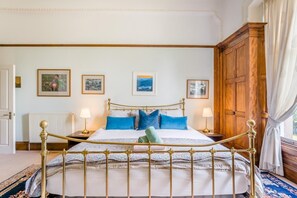 Ein Schlafzimmer mit einem Himmelbett, zwei Nachttischen, einem Heizkörper und gerahmten Bildern an der Wand.
