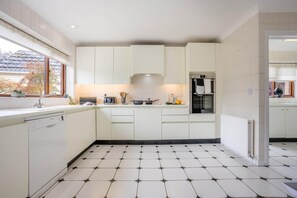 Eine moderne Küche mit weißen Schränken, einem eingebauten Backofen und einem Fenster für natürliches Licht.