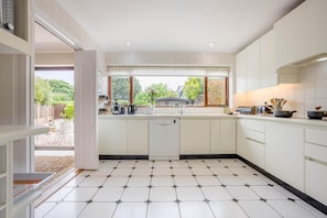 Eine moderne Küche mit Spülmaschine, Spüle und Fenster mit Blick auf einen Garten.