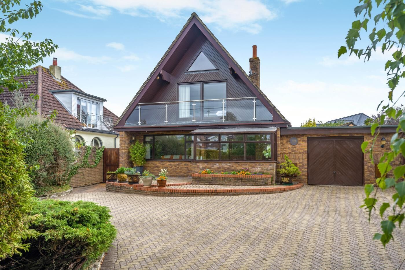 A modern house with a prominent gable roof, a large garage, and a paved driveway.