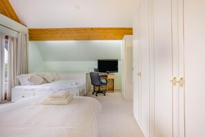 Ein Schlafzimmer mit einem Bett, einem Schreibtisch mit Computer und einem Kleiderschrank.