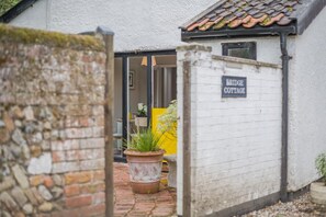 Eine Ziegelwand mit einem weißen Gebäude, auf dem 'Bridge Cottage' steht.