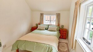 A bedroom with a bed, two nightstands, a window with curtains, and a wooden floor. - 2 Bed in Hoxne (oc-b45969) (Hoxne)